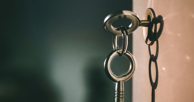 A metal key in a keyhole with a shadow on a wall