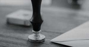 A wooden stamp sits on a wooden desk