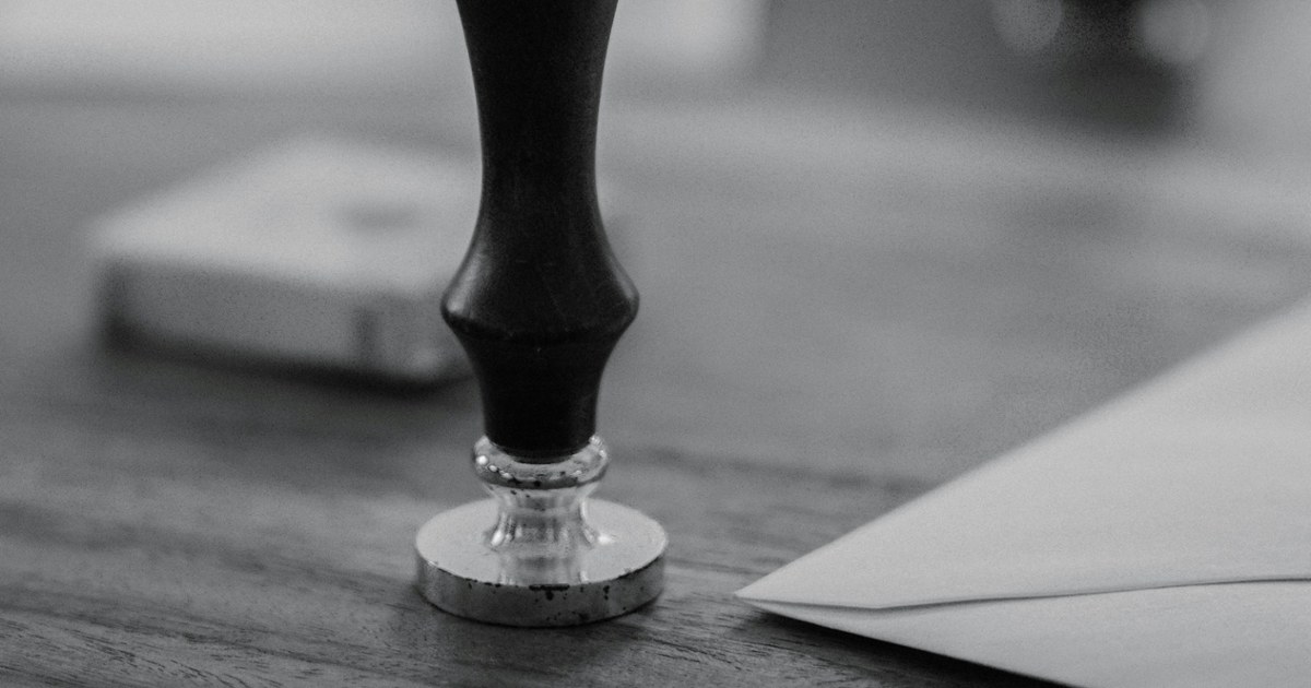A wooden stamp sits on a wooden desk